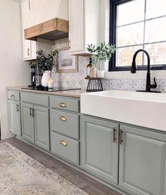 a kitchen with gray cabinets and white counter tops, black faucet above the sink