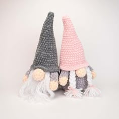 two crocheted gnomes sitting next to each other on top of a white surface