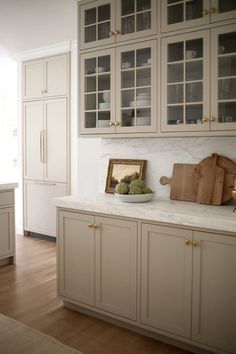 a kitchen with white cabinets and marble counter tops