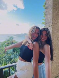 two women standing next to each other on a balcony