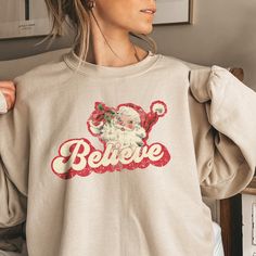 Cozy up to Christmas morning with our fun "I believe" retro Santa sweater. Ideal for any situation, a unisex heavy blend crewneck sweatshirt is pure comfort. Made from a polyester and cotton blend, they are so soft and cozy. CARE INSTRUCTIONSMachine wash: cold (max 30C or 90F); Non-chlorine: bleach as needed; Tumble dry: low heat; Do not iron; Do not dryclean. PRODUCT FEATURES The collar is ribbed knit, so it retains its shape even after washing. There are no itchy side seams on these sweaters. Made with a medium-heavy fabric blend of 50% cotton and 50% polyester The classic fit along with the crew neckline deliver a comfy wearing experience with a clean-cut style. Double-needle stitching at the shoulder, armhole, neck, waistband, and cuff seams add top-tier durability. Tear-away label Mad Santa Sweater, Santa Sweatshirt, Retro Santa, Santa Shirt, Santa Shirts, Oversized Crewneck, Sweater Oversized, Sweater Oversize, Sweatshirt Vintage