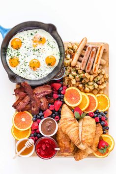 breakfast platter with eggs, sausages, fruit, and croissants