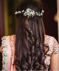 the back of a woman's head with long hair and flowers in her hair