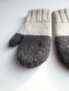 a pair of gray and white mittens sitting on top of a table