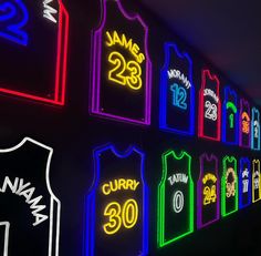 basketball jerseys are lit up on the wall with neon lights in front of them, along with numbers that spell out their name