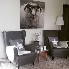 a living room with two gray chairs and a white rug on the floor in front of a painting