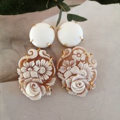 Flowers cameo earrings and white agate cabochon  Round white agate cabochons, 12mm diameter. Flower cameos engraved entirely by hand in Torre del Greco, the world capital of shell cameos manufacturing. These handcrafted cameos are deliberately not identical, to better enhance the uniqueness and authenticity of this jewel. The setting of the Flowers cameo earrings and white agate cabochon  is handcrafted in gilded 925 silver. The lobe attachment is with pin and butterfly. The length is 6 centimeters. Also available on request if not immediately available. In this case the processing times are 10 working days. Each cameo is unique as it is handmade, therefore any slight differences compared to the product photo are a guarantee of the authenticity of the chosen jewel. ------------------------ Cameo Earrings, Agate Cabochon, White Agate, Stone Work, Baroque Pearls, Jewelry Earrings Dangle, 925 Silver, Agate, Dangle Drop Earrings