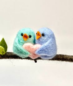 two needled birds sitting on a branch with one holding the other's hand