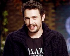 a man in a black sweater smiles at the camera