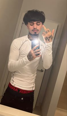 a man with tattoos taking a selfie in the mirror