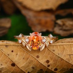 an orange diamond ring sitting on top of a leaf