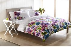 a bed with white sheets and colorful flowers on the comforter is in a room