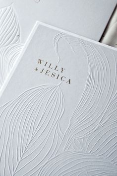 the wedding stationery is laid out on top of each other, with an embossed peacock design