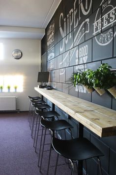 there are many chairs at the bar with plants on the wall behind them and in front of it