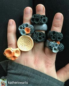 a person's hand with five different rings made out of clay and rock chips