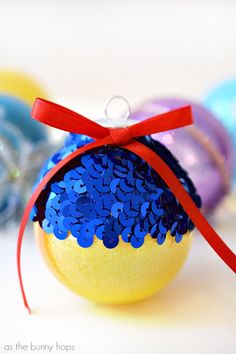 a yellow ornament with blue sequins and a red ribbon on it