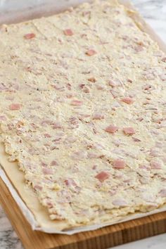 an uncooked pizza dough sitting on top of a wooden cutting board