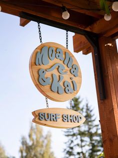 a wooden sign hanging from the side of a pergolated structure that reads, mom and dad surf shop