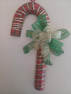 a red and green christmas decoration hanging on the wall next to a white wall with ribbon