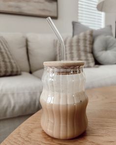 a glass jar with a straw inside sitting on a table in front of a couch