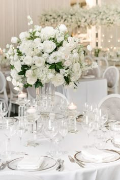 a table with white flowers and silverware is set for a formal dinner or reception