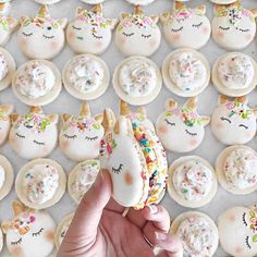 someone is holding an unicorn macaroni and cheese sandwich in front of a bunch of cupcakes