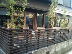 an outdoor deck with wooden chairs and bamboo trees in front of the building's windows