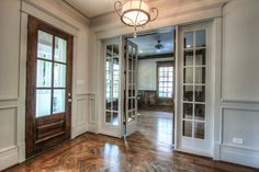 an empty room with wood flooring and glass doors leading to the other rooms in the house