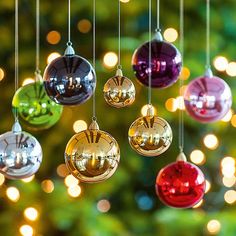 christmas ornaments hanging from strings with lights in the background