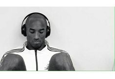 a man wearing headphones sitting in front of a white wall