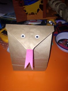 an origami elephant made out of brown paper with a pink ribbon on it