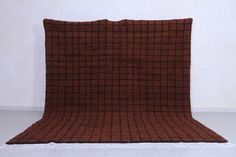 a brown and black checkered blanket sitting on top of a white floor next to a wall