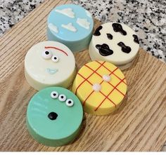 four decorated cookies sitting on top of a wooden cutting board