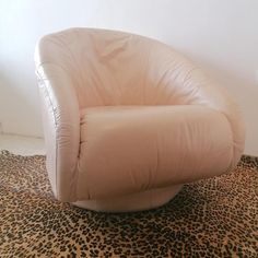 a white leather chair sitting on top of a leopard print flooring covered floor next to a wall