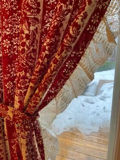 red and white curtains are hanging in front of a window with snow on the ground