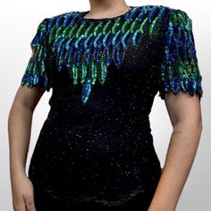 Brand Not Tagged Colors Green, blue, and black  Size Medium  Material Polyester and Silk Bust 34 Sleeve 9 Shoulder to hem 25 Details Short sleeve beaded black blouse. Blouse has green and blue sequins on the chest and sleeves. The back of the blouse has a long zipper. Evening Embellished Fitted Blouse, Embellished Short Sleeve Tops For Party Season, Beaded Tops For Night Out Party Season, Black Beaded Blouse For Party, Beaded Tops For Night Out And Party Season, Fitted Black Beaded Blouse, Vintage Formal Tops With Sequins, Vintage Formal Top With Sequins, Summer Formal Sequin Blouse