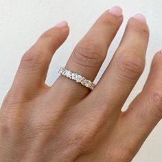 a woman's hand with a diamond ring on her left hand, showing the band