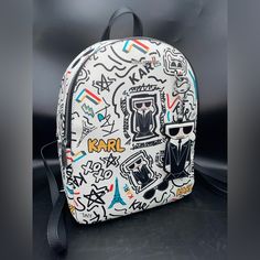 Awesome Karl Lagerfeld Paris Printed Backpack Adorable Hang Tag Keychain Which Is Removable Top-Zip Closure Silvertone Hardware One Inside Zip Pocket One Inside Slip Pocket Lined Polyurethane Imported Size Top Handle, 3" Drop Adjustable Backstraps, 12"-14" Drop 9.5"W X 12"H X 5"D Same/Next Business Day Shipping Trendy Leather Backpack For Errands, Designer Leather Backpack With Adjustable Strap For Errands, Designer School Backpack, Designer Everyday Backpack, Designer White Travel Backpack, Designer White Backpack For Travel, Designer Standard Backpack For Everyday Use, Designer Leather Backpack With Removable Pouch, Designer White Backpack For Everyday Use