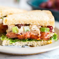 a sandwich with bacon, lettuce and other toppings sitting on a plate