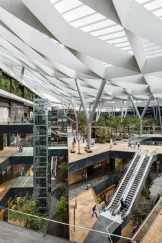 an indoor shopping mall with escalators, stairs and trees on the roof top