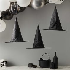 several black witches hats hanging from the ceiling with balloons in the air and a skull on the table