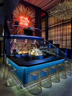 a bar with several stools in front of it and a neon sign above the bar