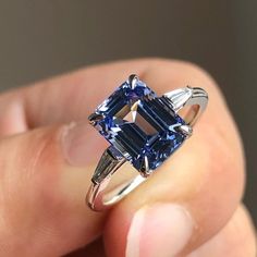 a person holding a ring with a blue and white diamond in it's center