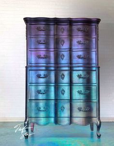 an old dresser is painted in blue and purple