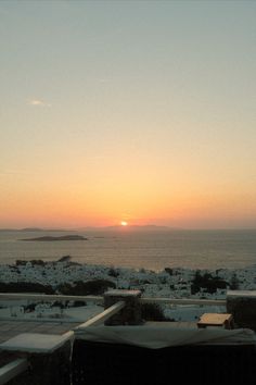 the sun is setting over the ocean with snow on the ground and lawn chairs in the foreground