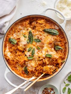 a casserole dish with cheese and spinach on the side next to two bowls