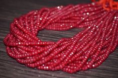 red seed beads are arranged on a wooden surface, with one bead in the middle