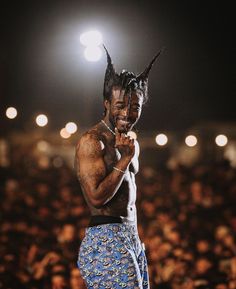 a man with dreadlocks on his head standing in front of an audience at a concert