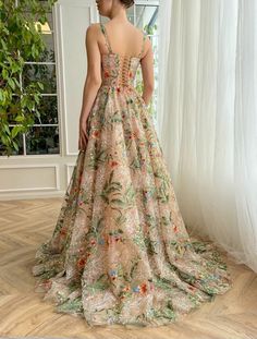 the back of a woman's dress with flowers on it, standing in front of a window