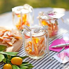 three jars filled with food sitting on top of a table next to some oranges